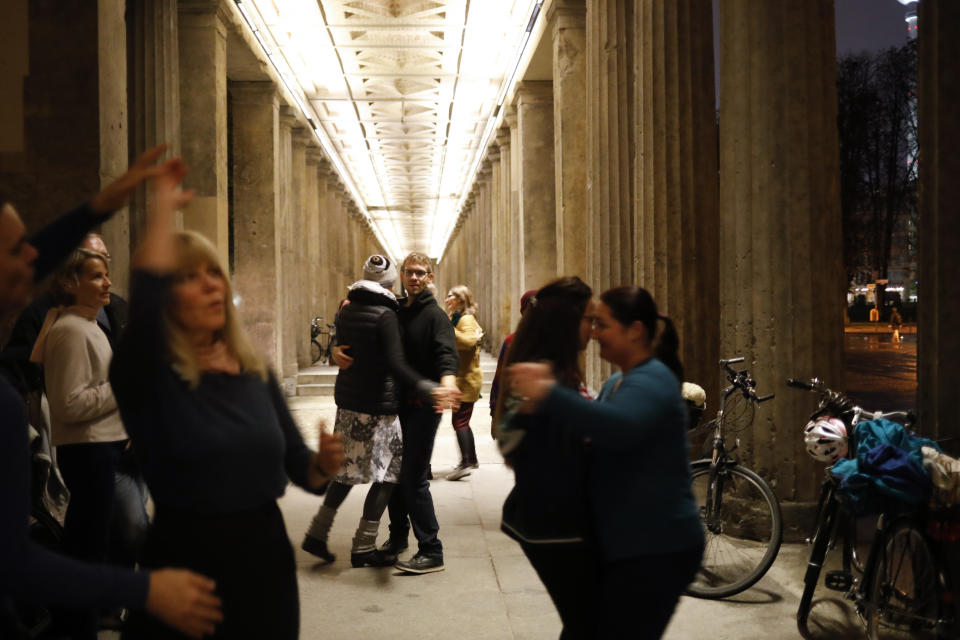 People attend an open air dance event by Harald Hertel's Jam Swingers in the colonnades of the Museum Island in Berlin, Germany, Friday, Oct. 23, 2020. In much of Europe, city squares and streets, be they wide, elegant boulevards like in Paris or cobblestoned alleys in Rome, serve as animated evening extensions of drawing rooms and living rooms. As Coronavirus restrictions once again put limitations on how we live and socialize, AP photographers across Europe delivered a snapshot of how Friday evening, the gateway to the weekend, looks and feels. (AP Photo/Markus Schreiber)