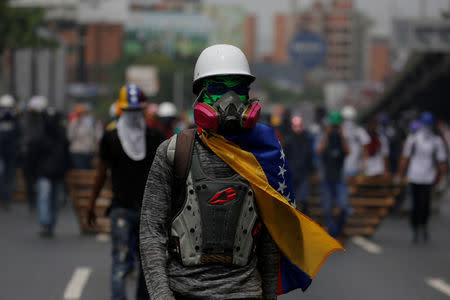 A demonstrator wearing a Venezuelan national flag walks next to others as they clash with riot security forces during a rally called by health care workers and opposition activists against Venezuela's President Nicolas Maduro in Caracas, Venezuela May 22, 2017. REUTERS/Carlos Barria