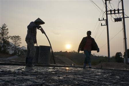 Men work on a petrol station construction site in Lak Sao October 27, 2013. REUTERS/Aubrey Belford