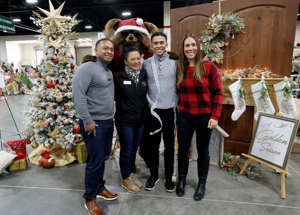 Jazz Bear photobombs a picture of David Fiefia, Becky Yamasaki, Festival of Trees executive board member, 17-year-old Afu Fiefia, who was diagnosed with Ewing sarcoma in 2021 and has been in remission for eight months, and Celestia Fiefia in front of a tree decorated by Yamasaki in honor of Afu, at the 53rd annual Festival of Trees to benefit Intermountain Primary Children’s Hospital patients, at the Mountain America Expo Center in Sandy on Monday, Nov. 27, 2023.