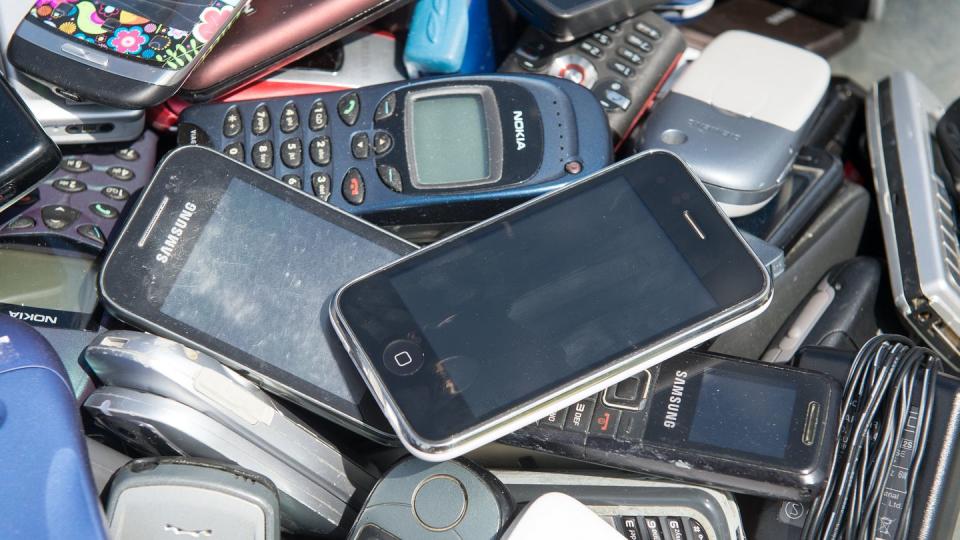 Alte Mobiltelefone liegen in einer Schubkarre.