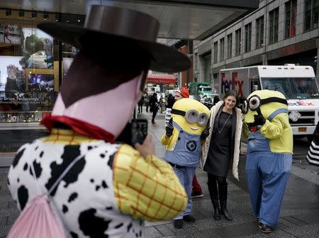 A woman poses with two people dressed as Minions as another dressed as Woody from Toy Story takes their photo in Times Square, in New York, April 7, 2016. REUTERS/Rickey Rogers