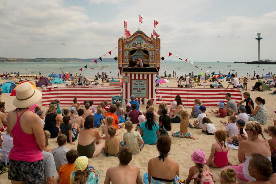 People watch a traditional Punch and Judy show on the beach (Getty Images)