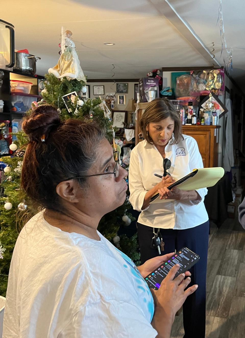 Betty Patina-Trujillo helps Dolores Davis of CG&S Design-Build make a list of repairs needed for the Trujillo family's home as part of Season for Caring.