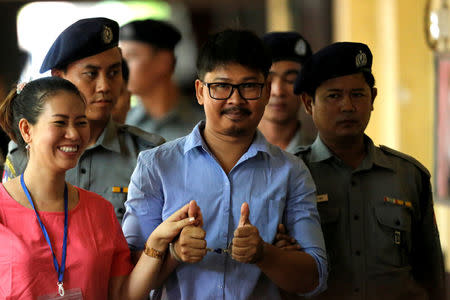 Detained Reuters journalist Wa Lone gives a 'two-thumbs-up' as he arrives with his wife Pan Ei Mon, escorted by police, before a court hearing in Yangon, Myanmar May 22, 2018. REUTERS/Ann Wang