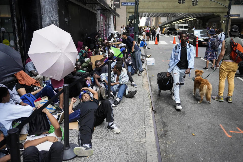 Immigrants wait in line outside the Roosevelt Hotel in New York City in July. Gov. Greg Abbott on Wednesday defended his program of busing migrants from Texas to cities across the nation where Democrats are in charge.
