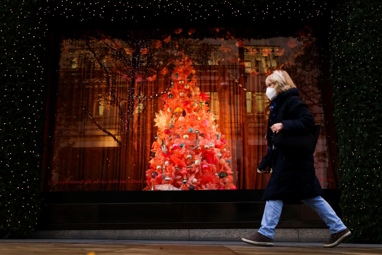 A pedestrian walks past a Christmas tree in a window display at Selfridges department store on Oxford Street, London