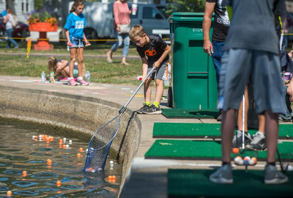 Brady Neal, 7, retrieves balls hit into the water at the Lagoon Golf event set up for the Pekin Marigold Festival.