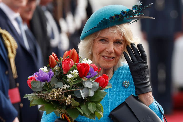 Camilla sostiene un ramo de flores mientras se sube a un automóvil después de aterrizar en el aeropuerto de Berlín Brandenburgo en Schoenefeld, cerca de Berlín, el 29 de marzo de 2023