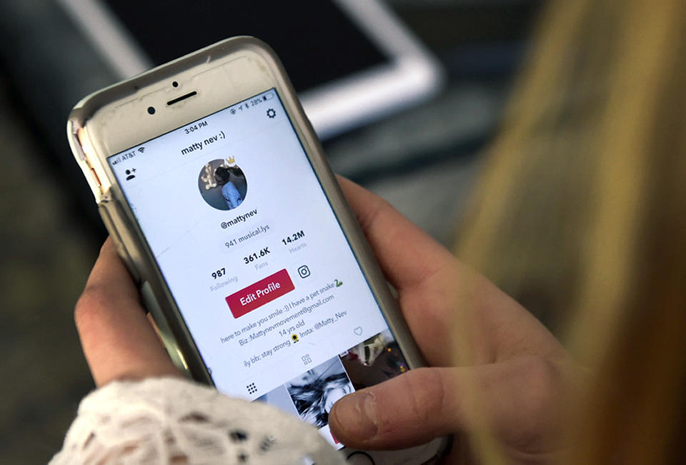 In this Feb. 28, 2018 photo, Matty Nev Luby holds her phone and logs into the lip-sync smartphone app Musical.ly, in Wethersfield, Conn. Teens and young adults say cyberbullying is a serious problem for people their age, but most don’t think they’ll be the ones targeted for digital abuse. The high school gymnast’s popularity on the lip-syncing app Musical.ly, which merged this summer into the Chinese video-sharing app TikTok, helped win her some modeling contracts. Luby said she's learned to navigate Instagram and other social media apps by brushing aside the anonymous bullies. (AP Photo/Jessica Hill)