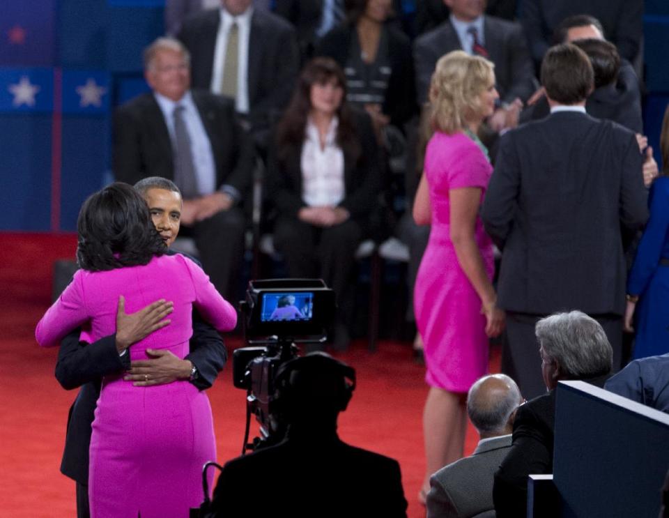 FILE - This Oct. 16, 2012 file photo shows President Barack Obama embracing first lady Michelle Obama on stage after presidential debate at Hofstra University in Hempstead, N.Y. Every year fashion offers up the good, the bad and the ugly. But what the industry is really built on _ and consumers respond to _ is buzz. The wives of the presidential candidates turned out to the second debate between Barack Obama and Mitt Romney in practically the same shade of hot pink. But they weren't by the same designer: Ann Romney's was by Oscar de la Renta, and Obama's by Michael Kors. (AP Photo/Carolyn Kaster)