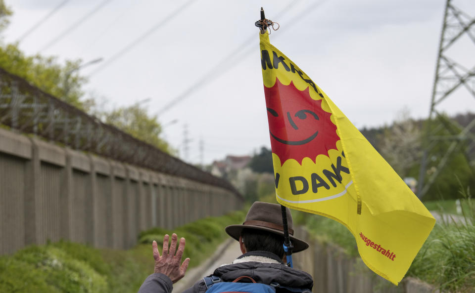 A man with an anti-nuclear flag walks past a fence at the nuclear power plant 'Isar 2' in Neckarwestheim, Germany, Saturday, April 15, 2023. Germany is shutting down the last three nuclear power plants today as a part of an energy transition agreed by successive governments. (Stefan Puchner/dpa via AP)