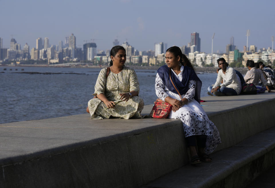 Sunita Sutar, right, speaks with a friend Nirmiti Bhor at Nariman Point in Mumbai, India, Sunday, March 19, 2023. In her village of Shirsawadi in India's Maharashtra state, girls were often married off when they turned 18, but Sutar ached for a different future. She focused on school, where she topped exam after exam. Today, she lives in Mumbai, India's frenetic financial capital, where she works as an auditor for the Indian Defence Department - a government job coveted by many young Indians for its security, prestige and benefits. (AP Photo/Rajanish Kakade)