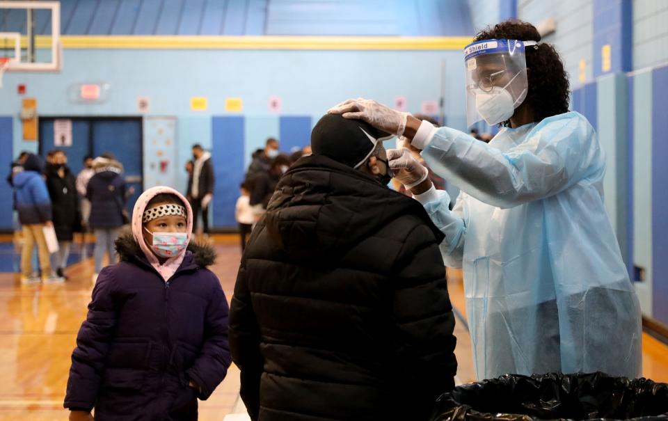 A nurse swabs the nasal passage of a person getting a rapid COVID-19 test at the Eugenio Maria de Hostos MicroSociety School, Dec. 30, 2021.