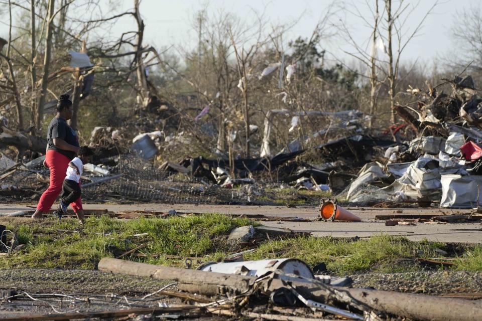 A pair of residents walk through the remains of their tornado demolished mobile home park, looking through the piles of debris, insulation, and home furnishings to see if anything is salvageable in Rolling Fork, Miss., Saturday, March 25, 2023. Emergency officials in Mississippi say several people have been killed by tornadoes that tore through the state on Friday night, destroying buildings and knocking out power as severe weather produced hail the size of golf balls moved through several southern states. (AP Photo/Rogelio V. Solis)