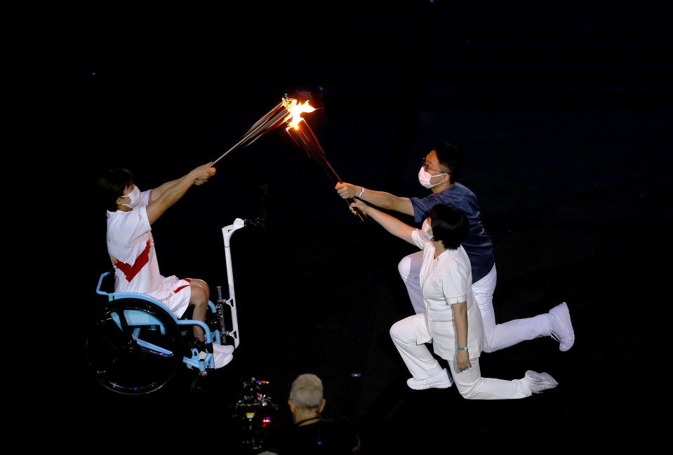 <p>TOKYO, JAPAN - JULY 23: The torch carriers exchange the flame of the Olympic torch during the Opening Ceremony of the Tokyo 2020 Olympic Games at Olympic Stadium on July 23, 2021 in Tokyo, Japan. (Photo by Laurence Griffiths/Getty Images)</p> 