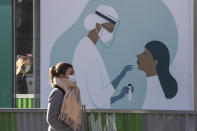 A woman walks past a billboard featuring a Covid test, displayed outside a pharmacy in Paris, Thursday, Nov. 5, 2020. In France, which is in a monthlong partial lockdown to stop fast-rising virus hospitalizations and deaths, the health minister may announce tighter measures at a weekly press conference later Thursday. (AP Photo Michel Euler)