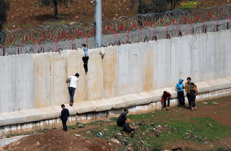 Internally displaced Syrian boys climb the wall in Atmah IDP camp, located near the border with Turkey