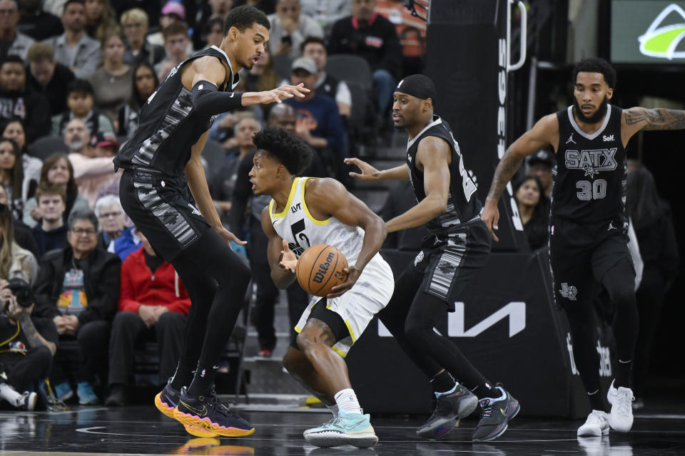 Utah Jazz's Collin Sexton (2) looks to pass as he is defended by San Antonio Spurs' Victor Wembanyama, left, Malaki Branham and Julian Champagnie (30) during the first half of an NBA basketball game Tuesday, Dec. 26, 2023, in San Antonio. (AP Photo/Darren Abate)