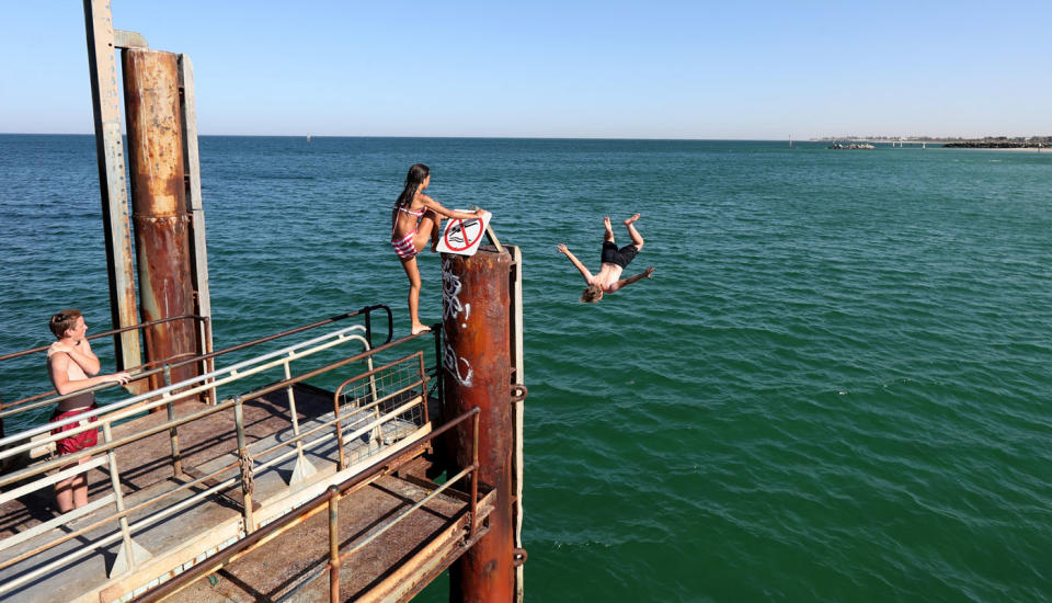 Swimmers are seen jumping off a jetty at Glenelg Beach. Source: AAP