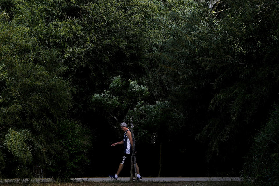 A man walks at a main park amid COVID-19 pandemic restrictions government in central capital Nicosia, Cyprus, Thursday, May 6, 2021. Cyprus has unveiled a phased rollback of COVID-19 lockdown restrictions over the next month including a shortened curfew and a reopening of all schools next week, but will enforce the compulsory display of proof of vaccination, virus testing or convalescence from the disease in areas were people gather in numbers, including restaurants and churches. (AP Photo/Petros Karadjias)