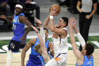 Phoenix Suns' Devin Booker, center, drives to the basket against multiple Milwaukee Bucks defenders during the second half of an NBA basketball game Monday, April 19, 2021, in Milwaukee. (AP Photo/Aaron Gash)