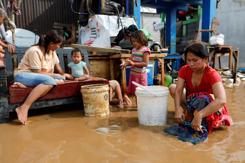 Woman washes clothes at an area affected by floods after heavy rains in Jakarta