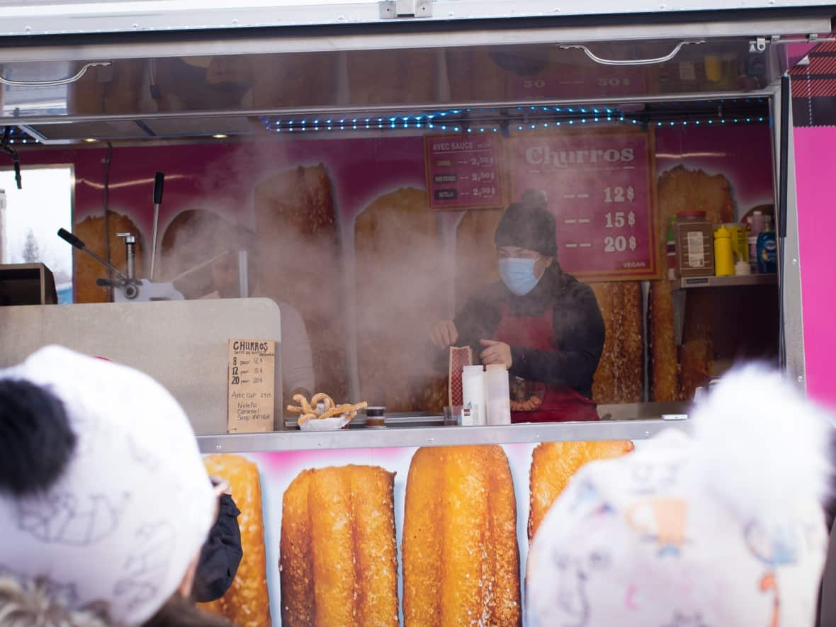 A worker is obscured by steam as they prepare an order of churros at the annual Aylmer Christmas market in Gatineau, Que., on Dec. 5, 2021, during the COVID-19 pandemic. (Trevor Pritchard/CBC - image credit)