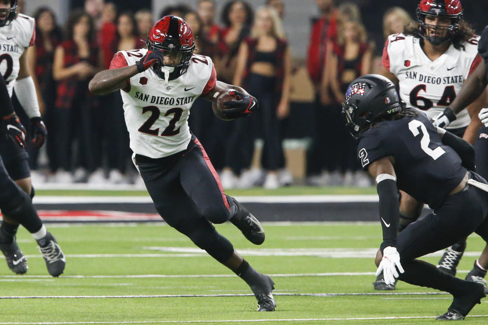 San Diego State running back Greg Bell (22) carries as UNLV defensive back Nohl Williams (2) defends during the first half of an NCAA college football game Friday, Nov. 19, 2021, in Las Vegas. (AP Photo/Chase Stevens)