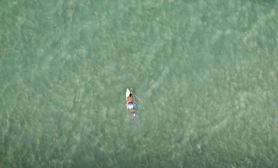 A surfer swims at Barra da Tijuca beach in Rio de Janeiro February 22, 2013. REUTERS/Ricardo Moraes (BRAZIL - Tags: TRAVEL SOCIETY SPORT TPX IMAGES OF THE DAY) - RTR3E4RH