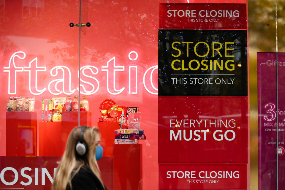 A woman wearing a face mask walks past stock clearance signs in the windows of the flagship branch of closing-down department store chain Debenhams on Oxford Street in London, England, on December 4, 2020. London has returned to so-called Tier 2 or 'high alert' coronavirus restrictions since the end of the four-week, England-wide lockdown on Wednesday, meaning a reopening of non-essential shops and hospitality businesses as the festive season gets underway. Rules under all three of England's tiers have been strengthened from before the November lockdown, however, with pubs and restaurants most severely impacted. In London's West End, Oxford Street and Regent Street were both busy with Christmas shoppers this afternoon, meanwhile, with the retail sector hoping for a strong end to one of its most difficult years. (Photo by David Cliff/NurPhoto via Getty Images)