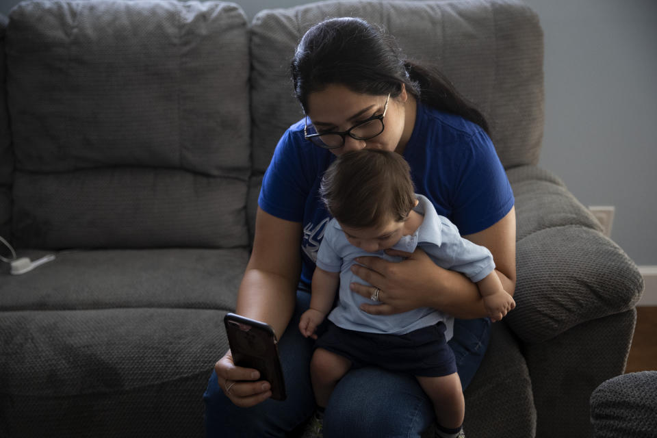 Sarvnaz Michel, a 28-year-old nurse who works in St. Jude Medical Center's COVID-19 unit, kisses her 6-month-old son, Arshan, while video chatting with her grandmother Tuesday, July 14, 2020, in Garden Grove, Calif. Michel's career has forced her to blur and blend her two lives. She agonizes over her every move in the hospital — "Did I put my gear on the right way, did I take it off the right way, did I touch something wrong accidentally?" — and locks her shoes in the car after her shifts. (AP Photo/Jae C. Hong)