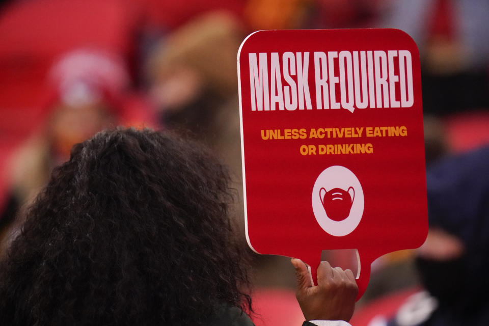 FILE - In this Jan. 3, 2021, file photo, an Arrowhead Stadium usher holds a mask required sign during the first half of an NFL football game in Kansas City. At least for now, U.S. health authorities say after being vaccinated, people should follow the same rules as everybody else about wearing a mask, keeping a 6-foot distance and avoiding crowds even after they’ve gotten their second vaccine dose. (AP Photo/Jeff Roberson, File)