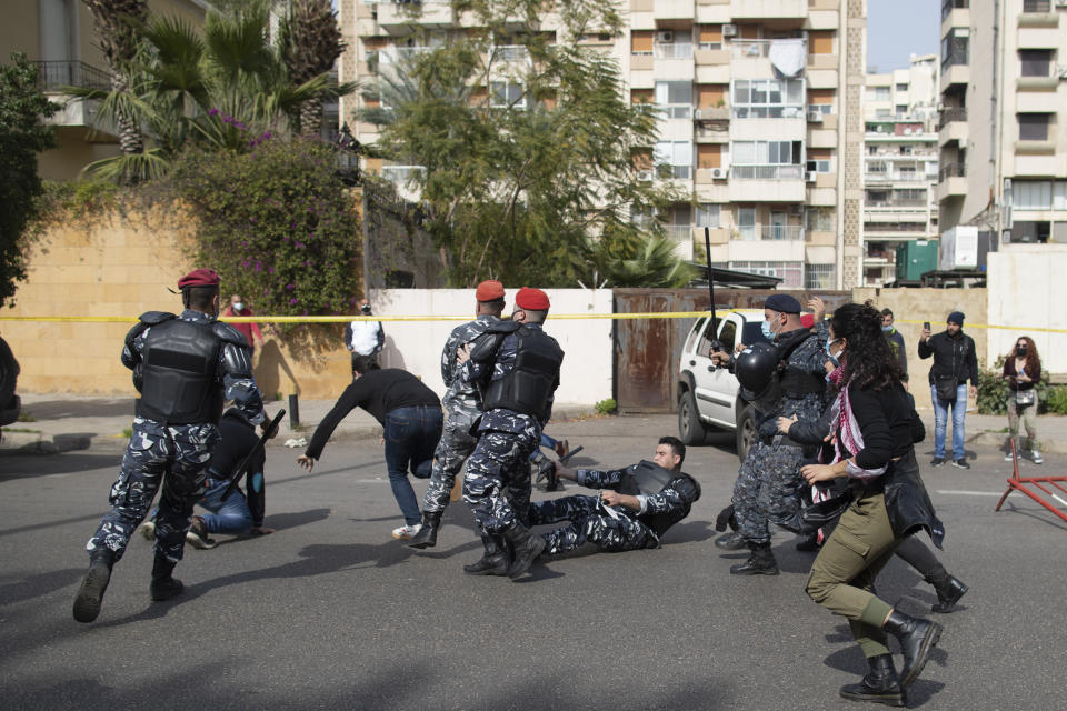 Riot police and army soldiers scuffle with anti-government protesters outside a military court in Beirut, Lebanon, Monday, Feb. 8, 2021. Riot police briefly clashed Monday in Beirut with hundreds of protesters demanding the release of anti-government activists detained following riots in northern Lebanon late last month. (AP Photo/Hassan Ammar)