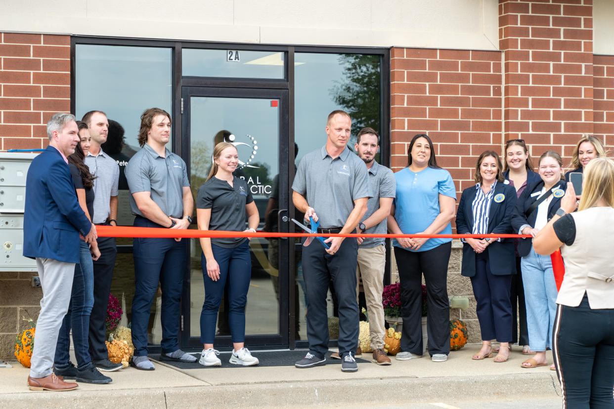 Former Iowa Hawkeye linebacker Mike Humpal (with scissors) is seen at a ribbon cutting ceremony Oct. 3 for his business, Humpal Chirpractic in North Liberty.