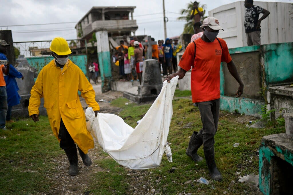 Men carry the body of a boy, who was found in a collapsed building, into the cemetery in Les Cayes, Haiti, Tuesday, Aug. 17, 2021, three days after a 7.2 magnitude earthquake hit. According to an engineer working for Les Cayes Mayor, the boy’s body was found Monday amid the rubble of a collapsed hostal. (AP Photo/Matias Delacroix)