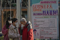An elderly man puts on his mask after getting his routine COVID-19 throat swab at a coronavirus testing site displaying a poster which encourages elderly citizen to get vaccination in Beijing, Sunday, Dec. 4, 2022. China on Sunday reported two additional deaths from COVID-19 as some cities move cautiously to ease anti-pandemic restrictions amid increasingly vocal public frustration over the measures. (AP Photo/Andy Wong)