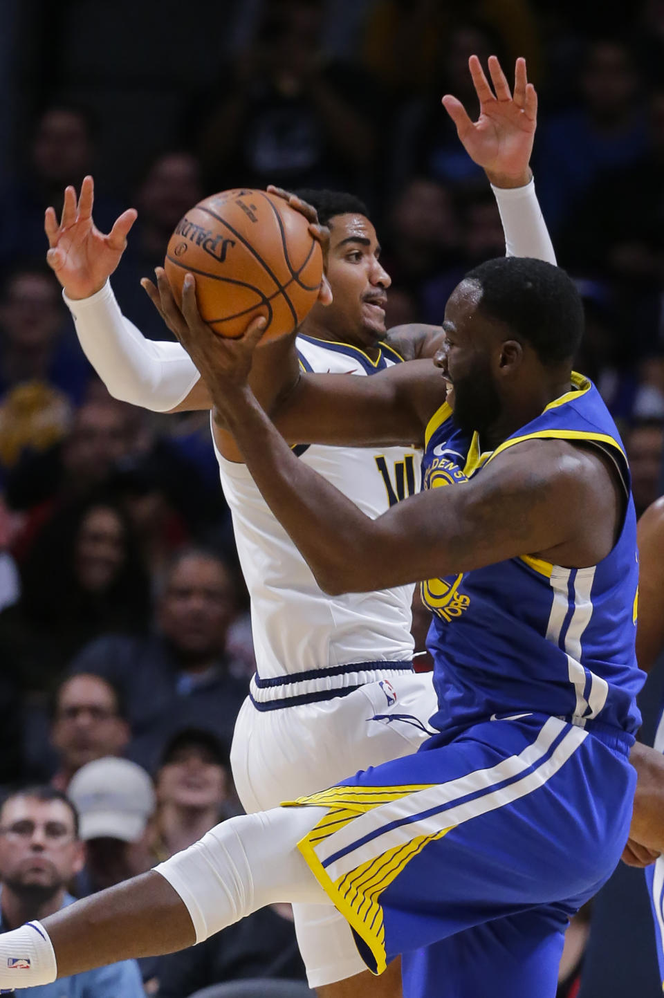 Golden State Warriors forward Draymond Green (23) pulls down a rebound against Denver Nuggets guard Gary Harris (14) during the first quarter of an NBA basketball game, Sunday, Oct. 21, 2018, in Denver. (AP Photo/Jack Dempsey)