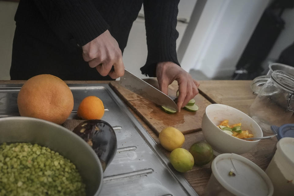 Josh Spodek prepares fresh produce for fermentation as part of a diet that supports a sustainable lifestyle of near zero consumption, Tuesday Jan. 24, 2023, in New York. Spodek cooks with an electric pressure cooker which is powered with a portable solar panel and battery pack at his Greenwich Village apartment. (AP Photo/Bebeto Matthews)