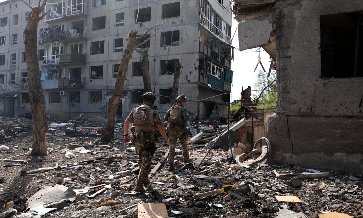 <span>Special police officers walk past destroyed buildings and debris during the evacuation of local residents from the village of Ocheretyne on 15 April.</span><span>Photograph: Anatolii Stepanov/AFP/Getty Images</span>