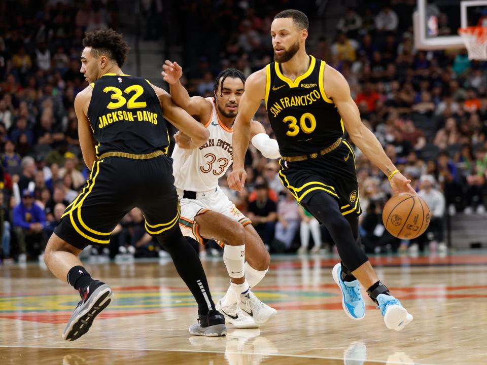 SAN ANTONIO, TX - MARCH 31: Stephen Curry #30 of the Golden State Warriors drives around a screen set by Trayce Jackson-Davis #32 against Tre Jones #33 of the San Antonio Spurs in the first half at Frost Bank Center on March 31, 2024 in San Antonio, Texas. NOTE TO USER: User expressly acknowledges and agrees that, by downloading and or using this photograph, User is consenting to terms and conditions of the Getty Images License Agreement. (Photo by Ronald Cortes/Getty Images)