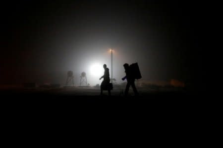 FILE PHOTO: A group of migrants who said they were from Djibouti and Somalia walk along railway tracks after crossing the Canada-U.S. border in Emerson, Manitoba, Canada, March 27, 2017.   REUTERS/Chris Wattie/File Photo