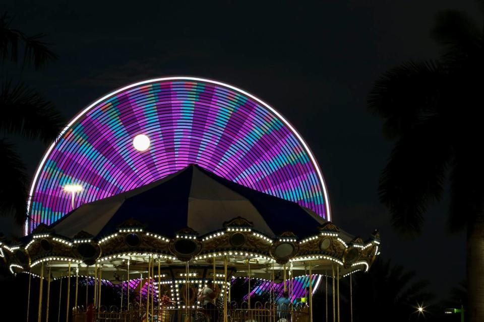 A view of one of the Ferris wheels as the moon rises during the opening day of the Miami-Dade County Youth Fair in 2022.