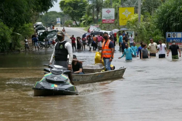 A member of the Navy helps transport items during flooding in Ilheus, located in Brazil's Bahia State, on December 27, 2021 (AFP/Camila SOUZA)