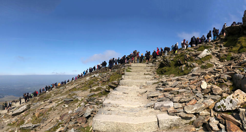 Dozens of people queue on the mountain top at Mount Snowdon