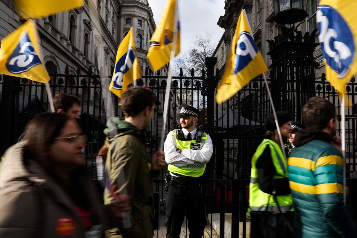Demonstrators wave flags of the PCS trade union as they march by Downing Street (AFP/Getty)