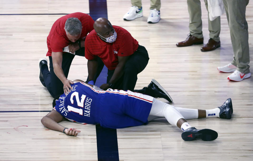 Philadelphia 76ers forward Tobias Harris (12) is attended to after hitting his head against the Boston Celtics during the third quarter of Game 4 of an NBA basketball first-round playoff series, Sunday, Aug. 23, 2020, in Lake Buena Vista, Fla. (Kim Klement/Pool Photo via AP)