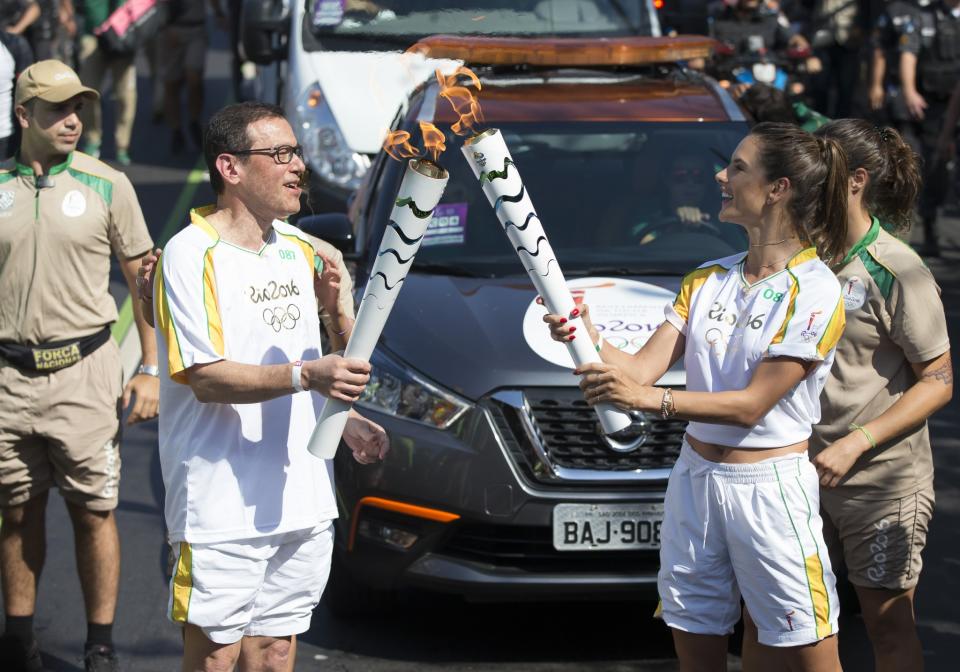 <p>Coca-Cola Torch Bearer Alessandra Ambrosio (R) has the ultimate #ThatsGold moment as she runs with the Olympic flame through Rio de Janeiro on August 5, 2016 in Rio de Janeiro, Brazil. (Photo by Buda Mendes/Getty Images for Coca-Cola) </p>