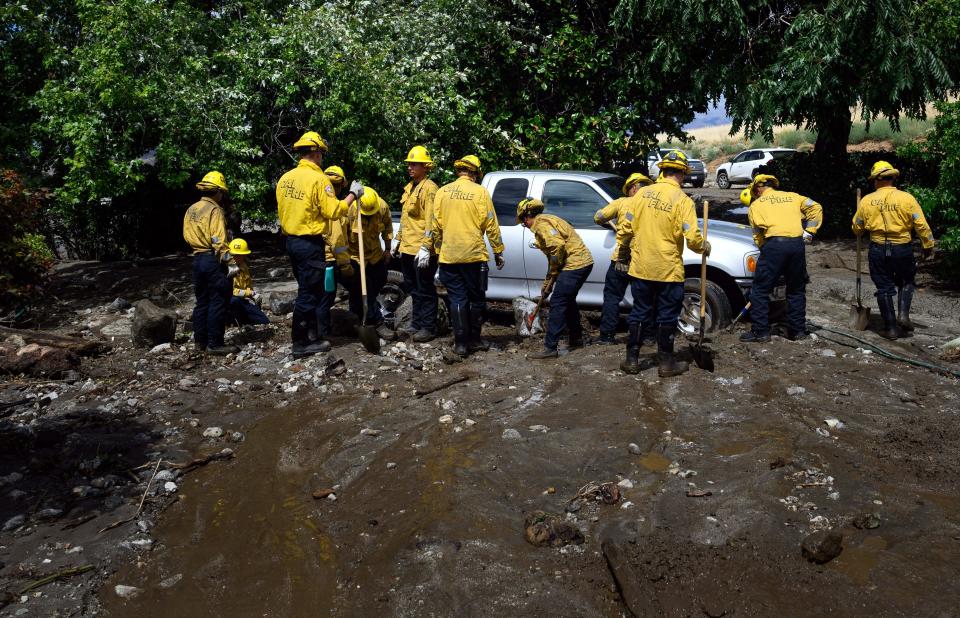 Firefighters working to remove mud and debris