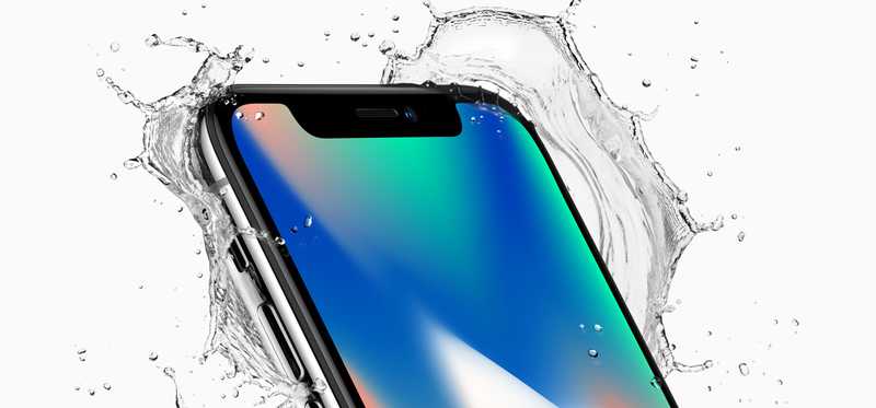 An iPhone X with water splashing around it.